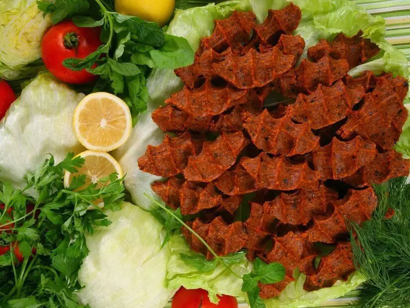 adıyaman çiğ köftesi tabak üzerinde yanında yeşillikler görünümü