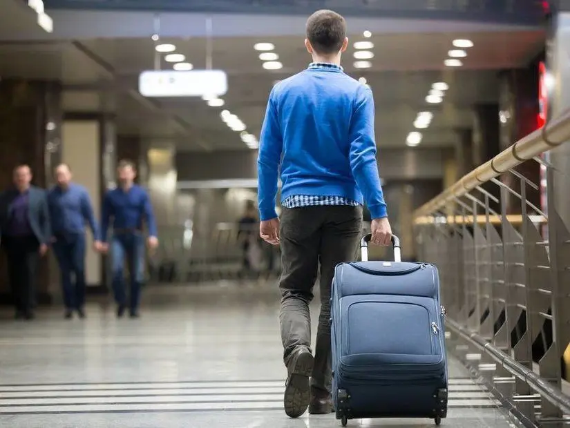 havaalanında uçuşa yetişmek için check-in kontuarına bagajını teslim etmeye giden yolcu
