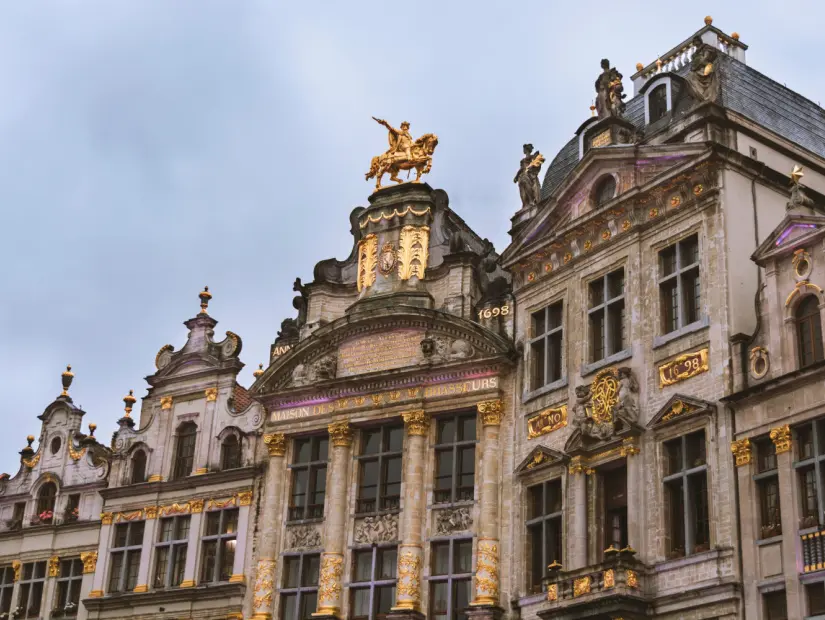 Belçika Bira Üreticileri Müzesi Çeşitli altın süs eşyaları, çiçekler ve heykellerle Barok tarzındaki Gran Place binalarının cephesinin kısmi görünümü.