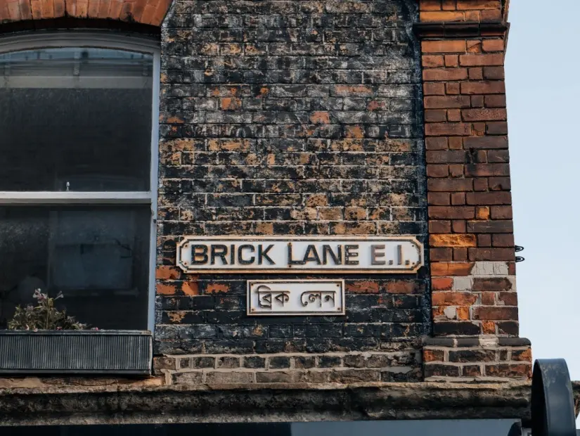 Brick Lane, Londra, İngiltere'deki bir binada İngilizce ve Bengalce iki dilli sokak adı tabelası.