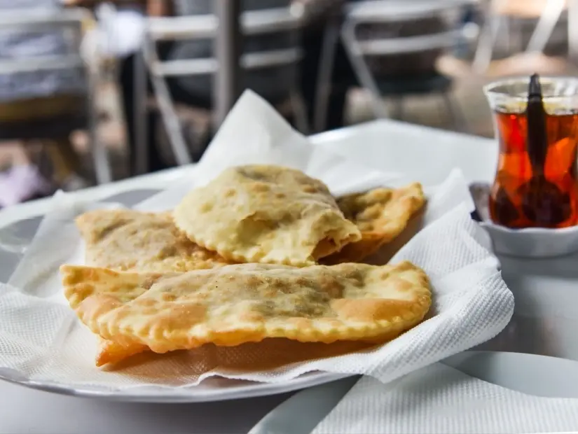 beyaz peçeteler üzerinde çiğ kıyma, soğan ve baharatlarla yapılan 'çi börek' adı verilen geleneksel kızarmış hamur işi