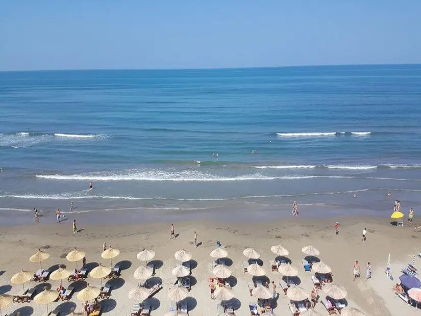 kosova plajı denizde yüzen insanlar ve güneşli günde şezlongda dinlenen misafirler