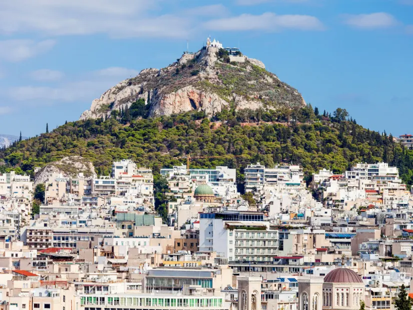Yunan başkentinin güzel şehir manzarası , Lycabettus Dağı'nın arka planında Atina şehri ve güneşli bir öğleden sonra mavi gökyüzü
