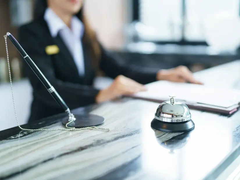 Lobideki masada üniformalı otel resepsiyonisti Otel resepsiyon masasında güler yüzlü ve misafirperver personel.