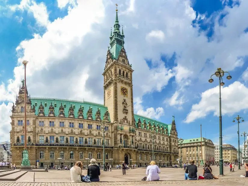 Hamburg, Almanya'nın Altstadt semtindeki Binnenalster Gölü yakınındaki pazar meydanında dramatik bulutlar ve mavi gökyüzü ile ünlü Hamburg belediye binasının güzel manzarası