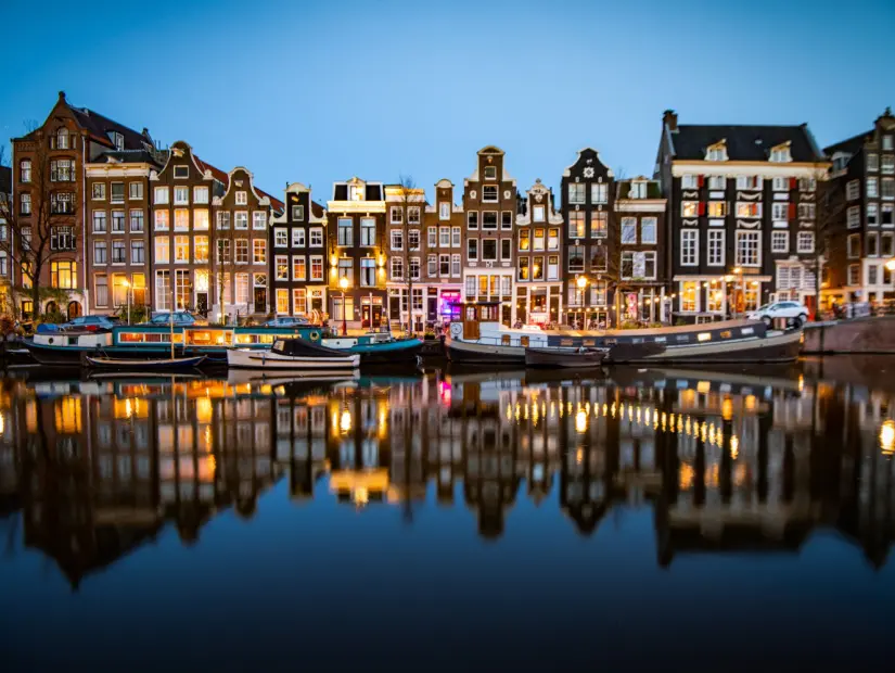 Kıyı boyunca tarihi binaların bulunduğu Amsterdam'daki Singel kanalının gece çekimi