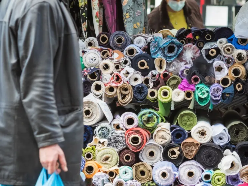Londra'daki Walthamstow pazarında bir müşteriyle birlikte satışa sunulan tekstil kumaş ruloları